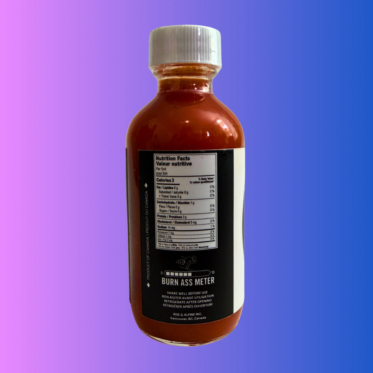 Rise & Alpine Hot Sauce, Ski Fast Burn Ass Tropical Ski Sauce.Side View of bottle. Tropical Flavour. Burn Ass meter. 